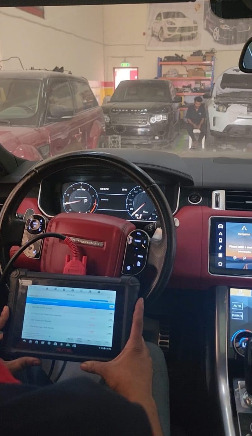 A technician running a diagnostic scan from a tablet inside a Range Rover cabin