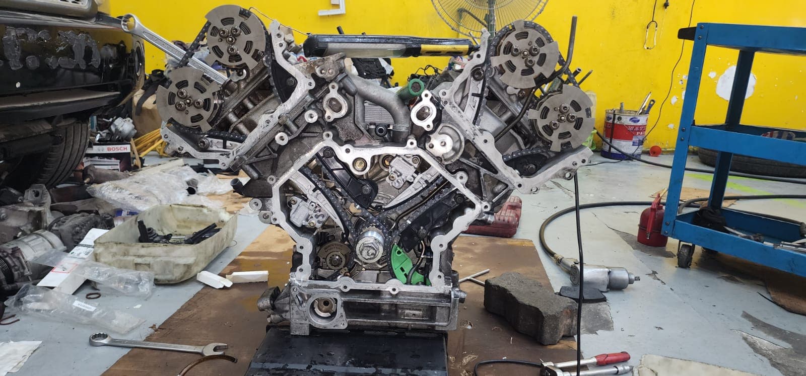 A stripped V-configuration engine with cylinder heads removed, laid out on the bench for rebuild